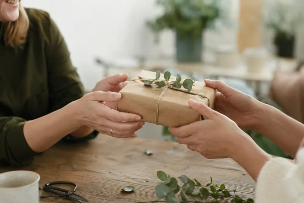 Zwei Menschen überreichen einander ein nachhaltig verpacktes Geschenk